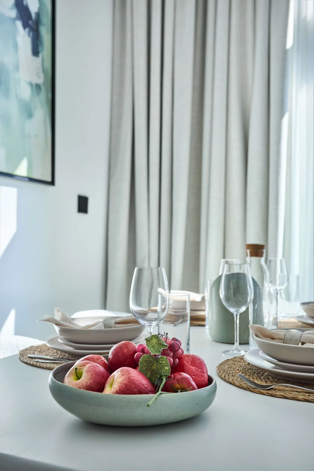 Una mesa de comedor está puesta con platos y un cuenco de fruta fresca.