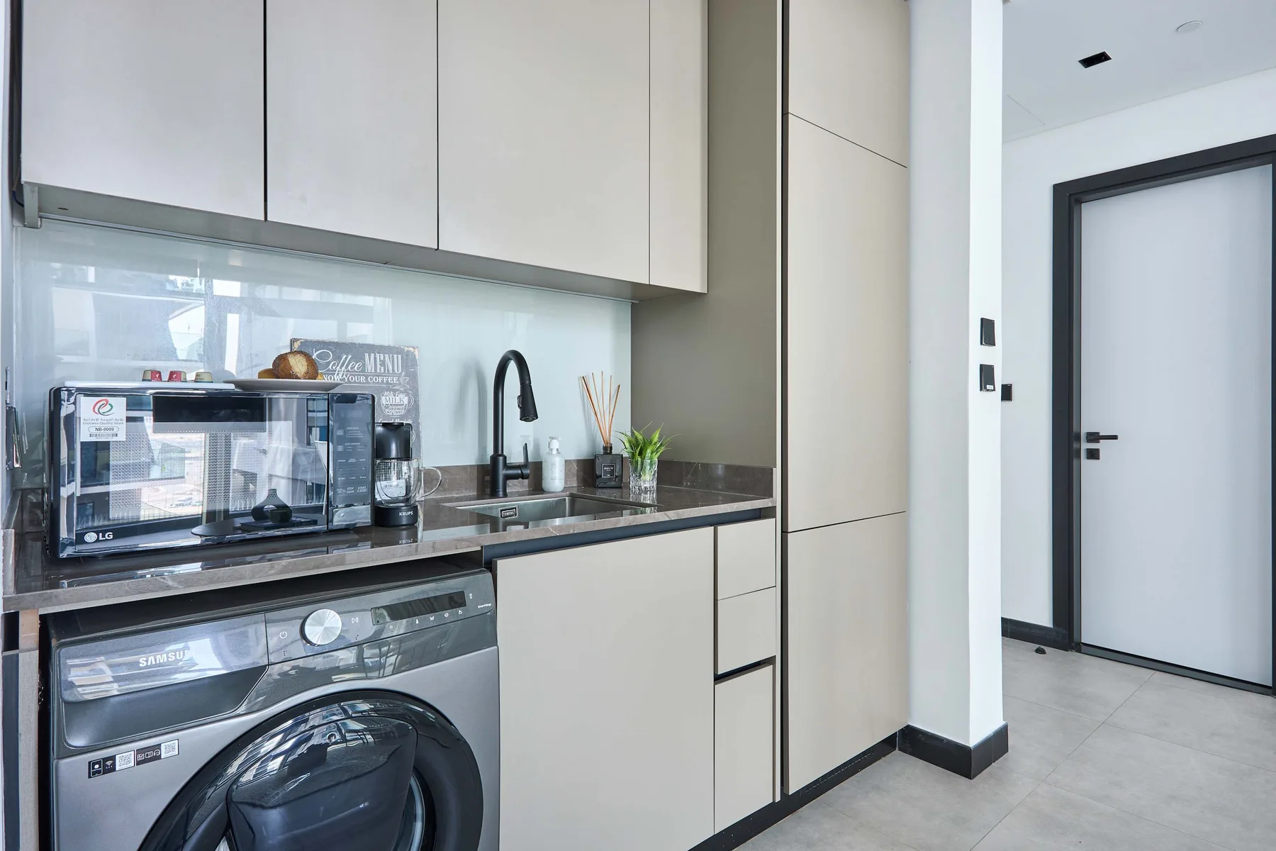 Una cocina compacta con un microondas sobre la encimera y una lavadora debajo.