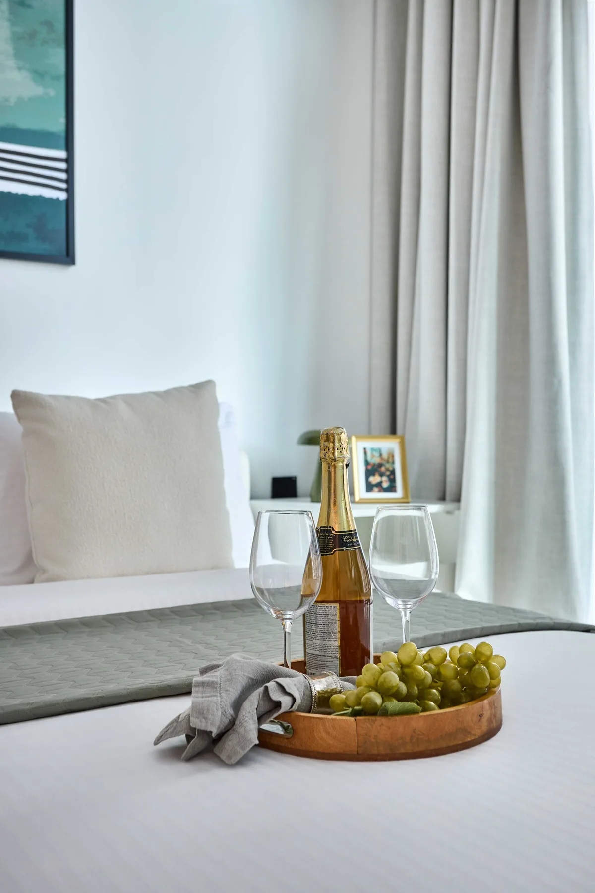 Dormitorio con una bandeja de uvas y una botella sobre la cama.