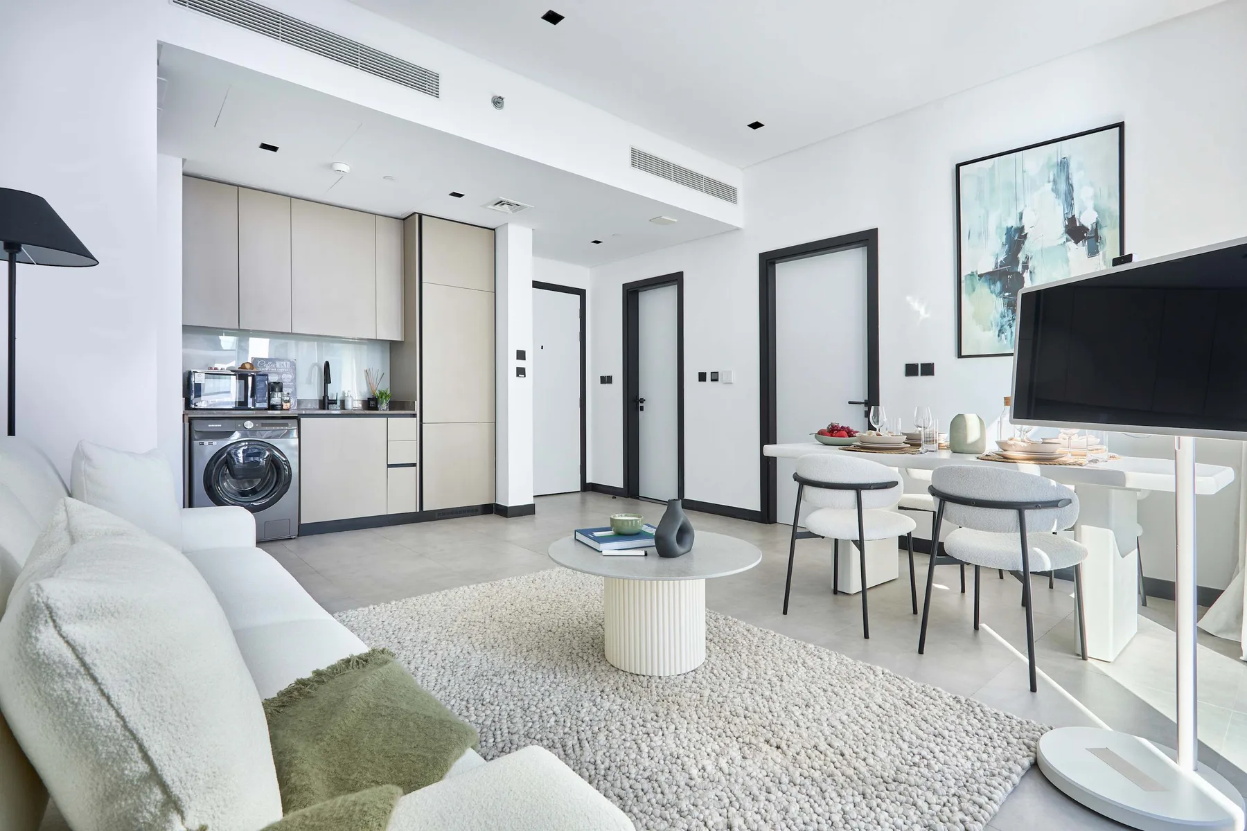 Una luminosa sala de estar y comedor con cocina compacta y asientos.