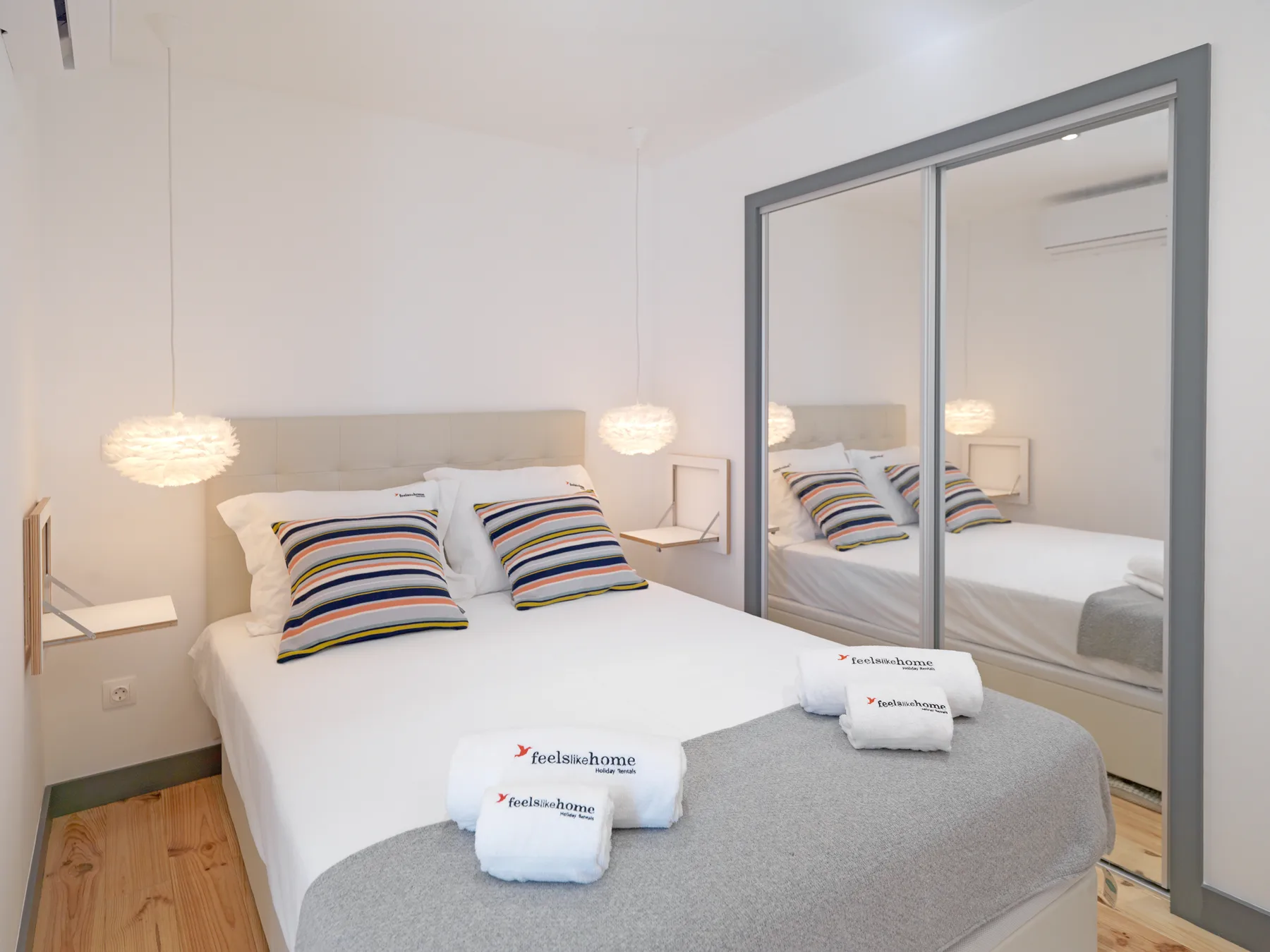 Un dormitorio con una cama bien hecha y puertas de armario con espejo.