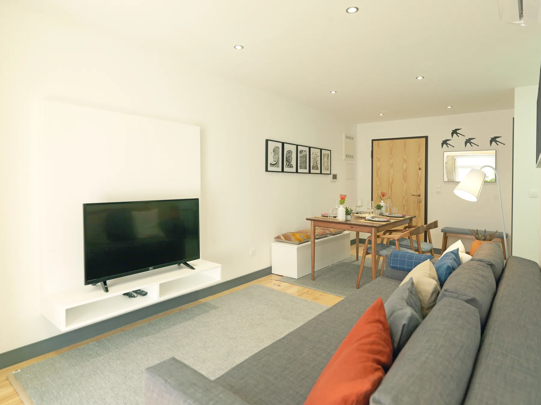 Una sala de estar y comedor con televisor, mesa y asientos.