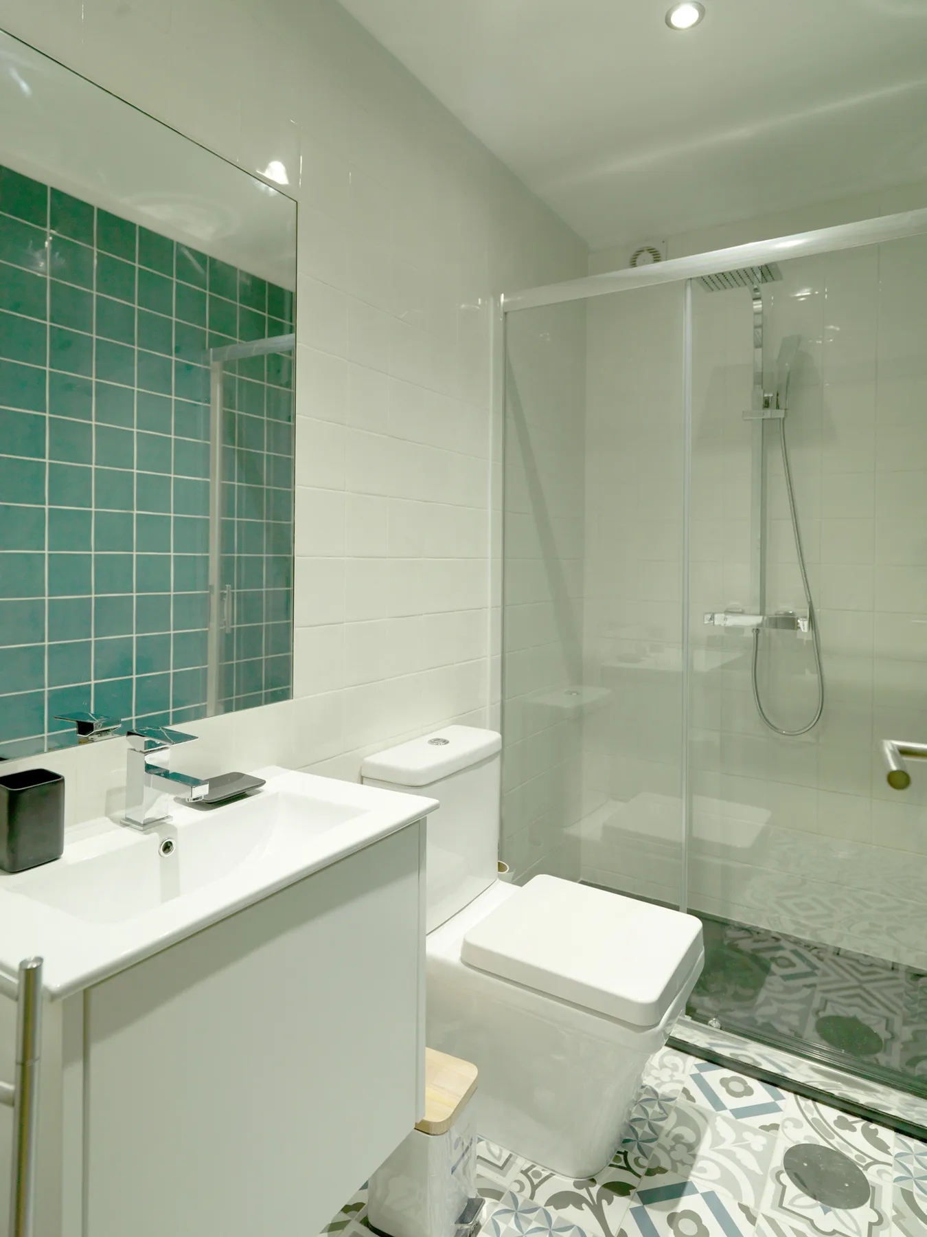 Un baño luminoso con lavabo, inodoro y ducha de vidrio.