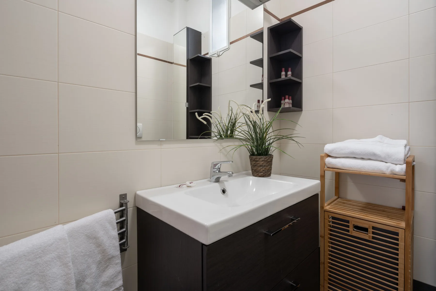 A tiled bathroom with a sink, mirror, and folded towels.