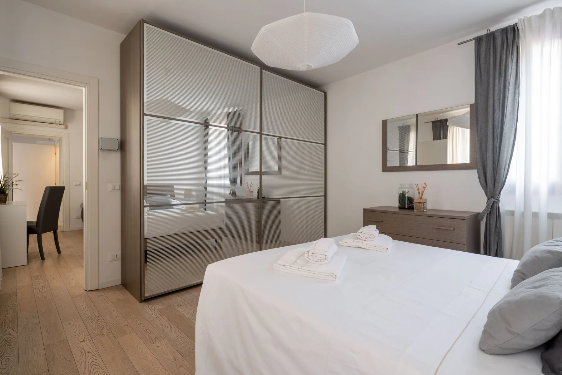 A bright bedroom with a neatly made bed and a large wardrobe.