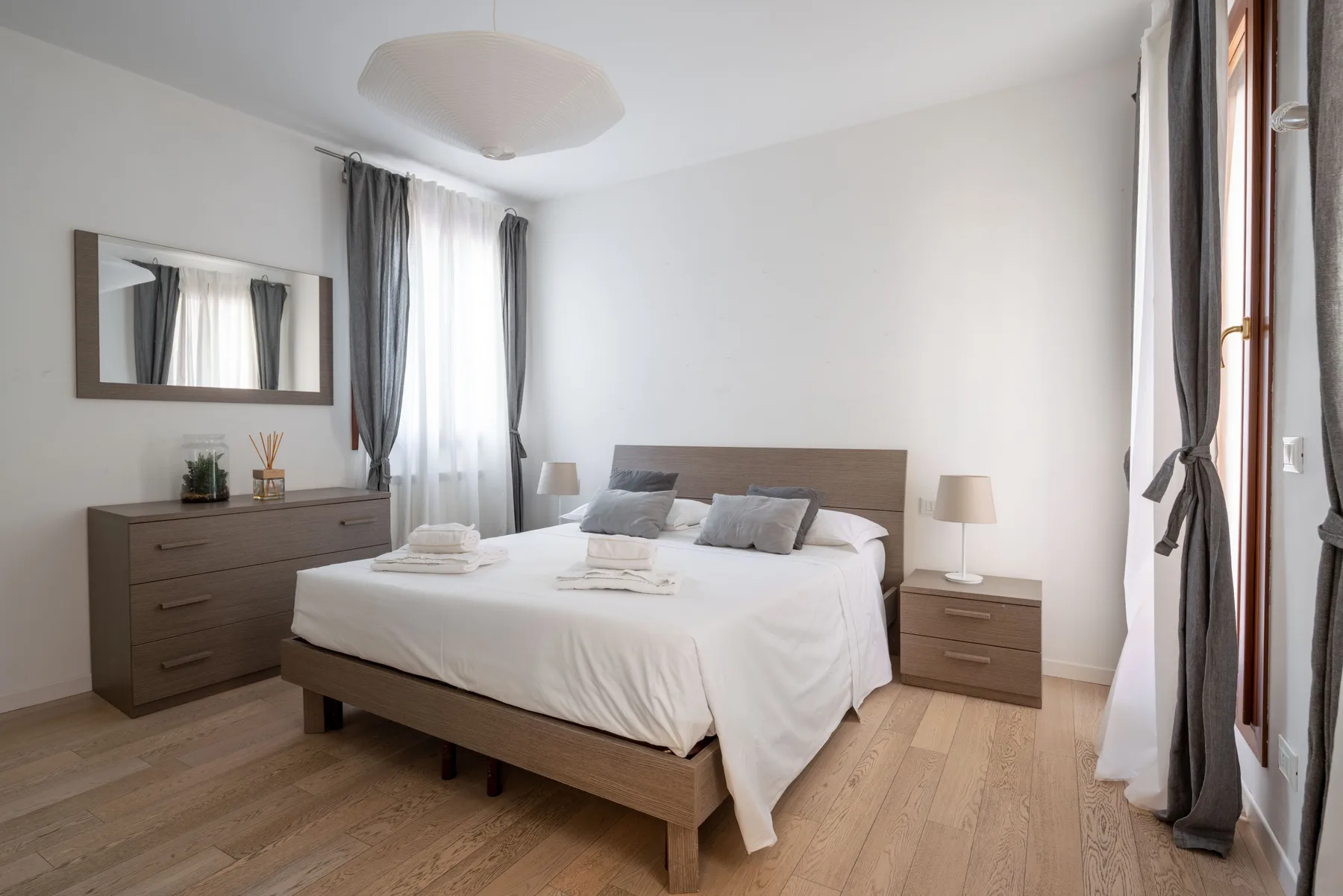 A bright bedroom with a neatly made bed and matching bedside tables.