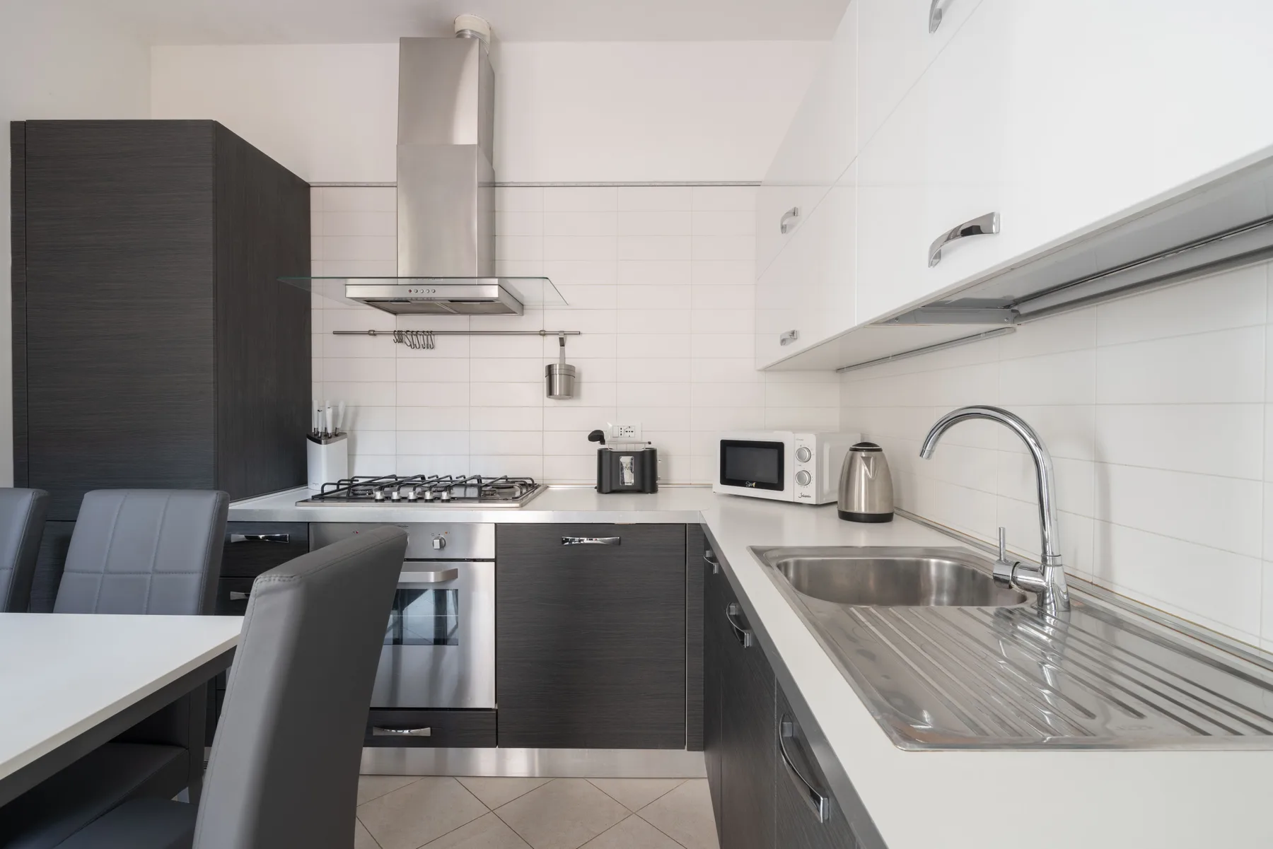 A modern kitchen with dark cabinetry, a cooktop, and a sink.