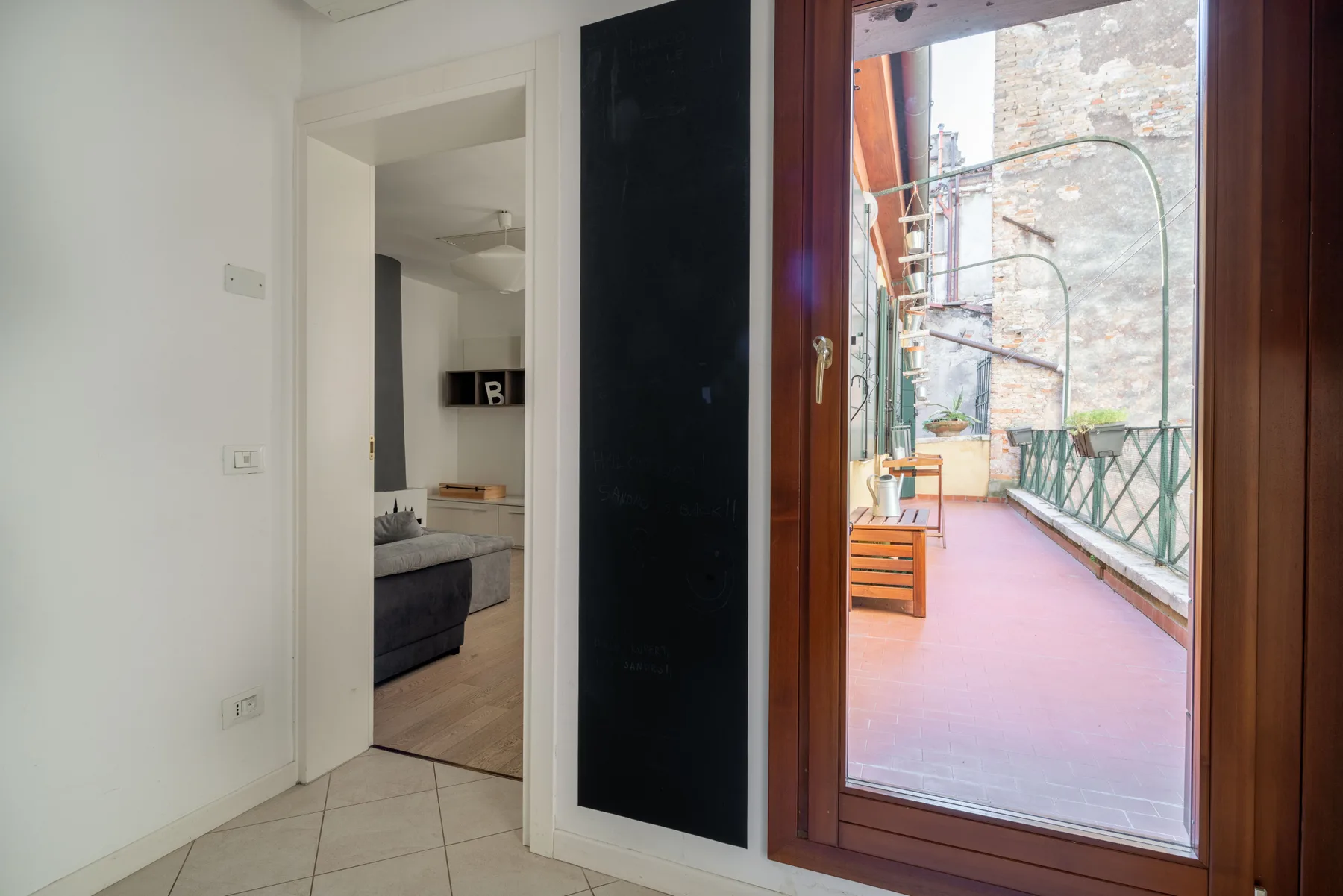 A bright interior opens onto a narrow balcony with outdoor seating.
