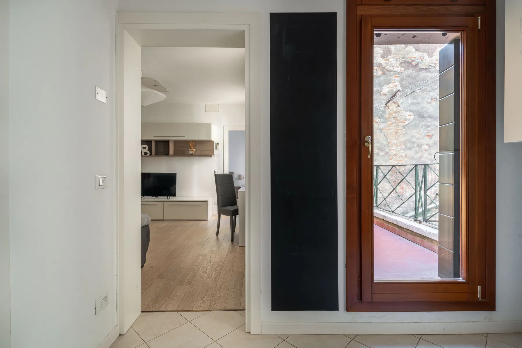 A doorway opens onto a bright living area with a table and seating.