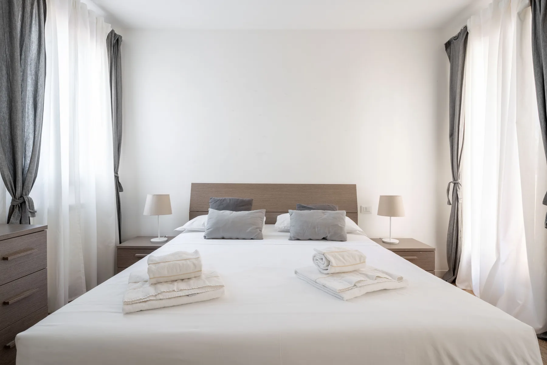 Un dormitorio luminoso con una cama bien hecha y toallas dobladas.