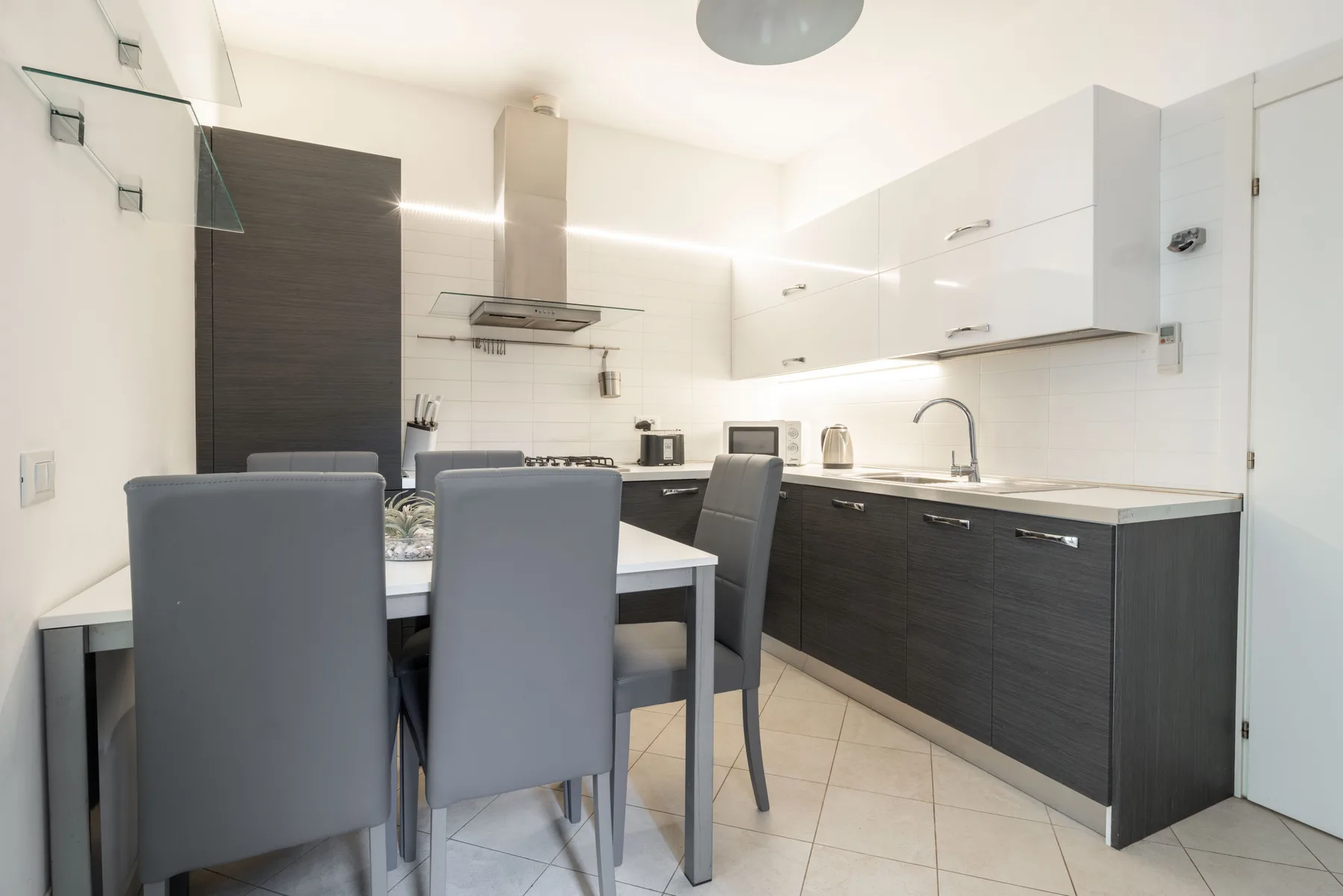 A modern kitchen and dining area with dark cabinets and a table.
