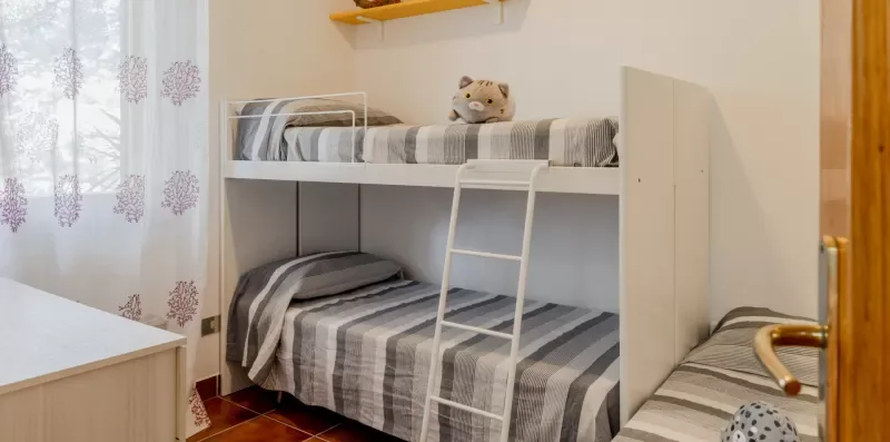 A bedroom with a bunk bed dressed in striped bedding.