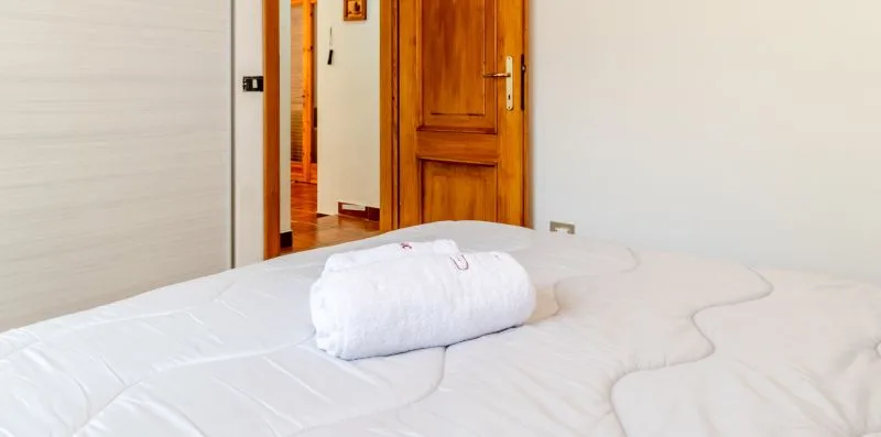 A bedroom with a white bed and a wooden door.