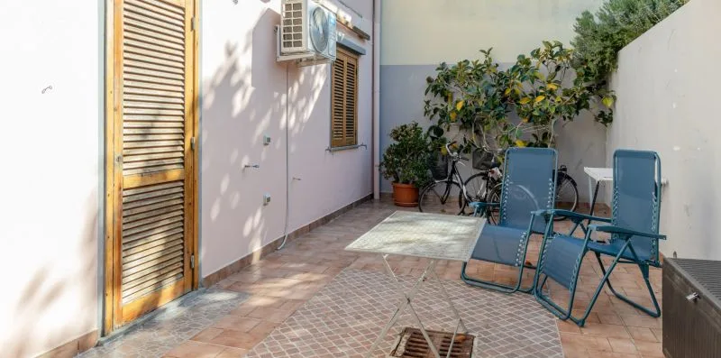 A tiled outdoor patio with blue seating and potted plants.