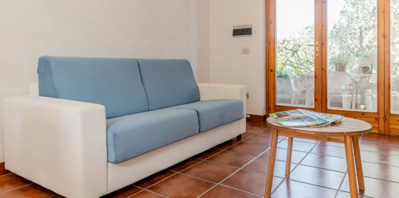A living room with a blue sofa and a small table beside glass doors.