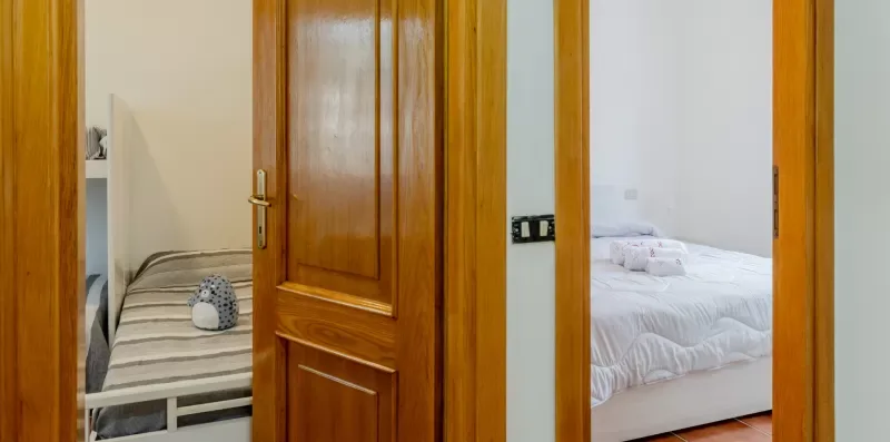 A bedroom with a bed and a single bed visible through open doorways.