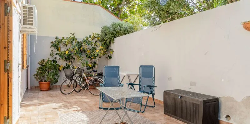 An outdoor patio with seating, potted plants, and a tiled floor.