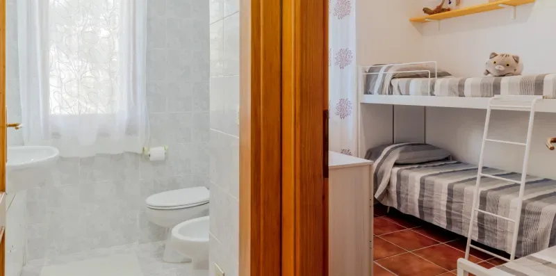 A bathroom and bunk-bed sleeping area are visible through an open doorway.