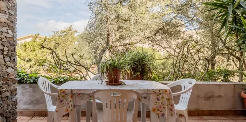 An outdoor dining area with a table and chairs beside a garden.