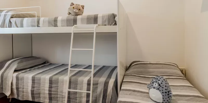 A bedroom with striped bedding on bunk beds and a separate single bed.