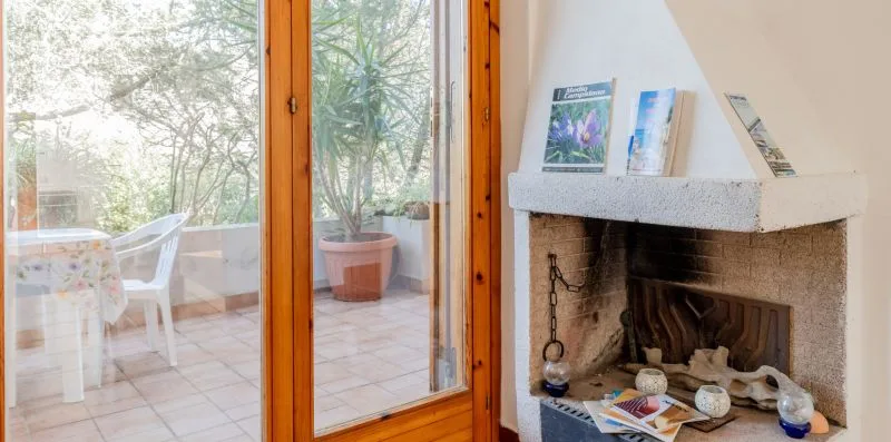 A living area with a stone fireplace beside glass doors opening onto a patio.