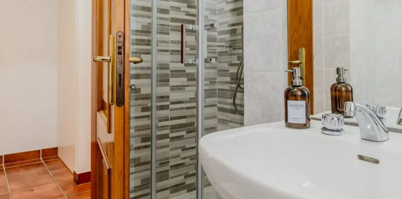 A bathroom with a white sink beside a glass-enclosed shower.
