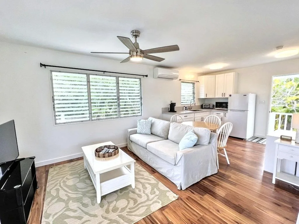 A bright living room opens onto a compact kitchen, with a sofa and dining table.