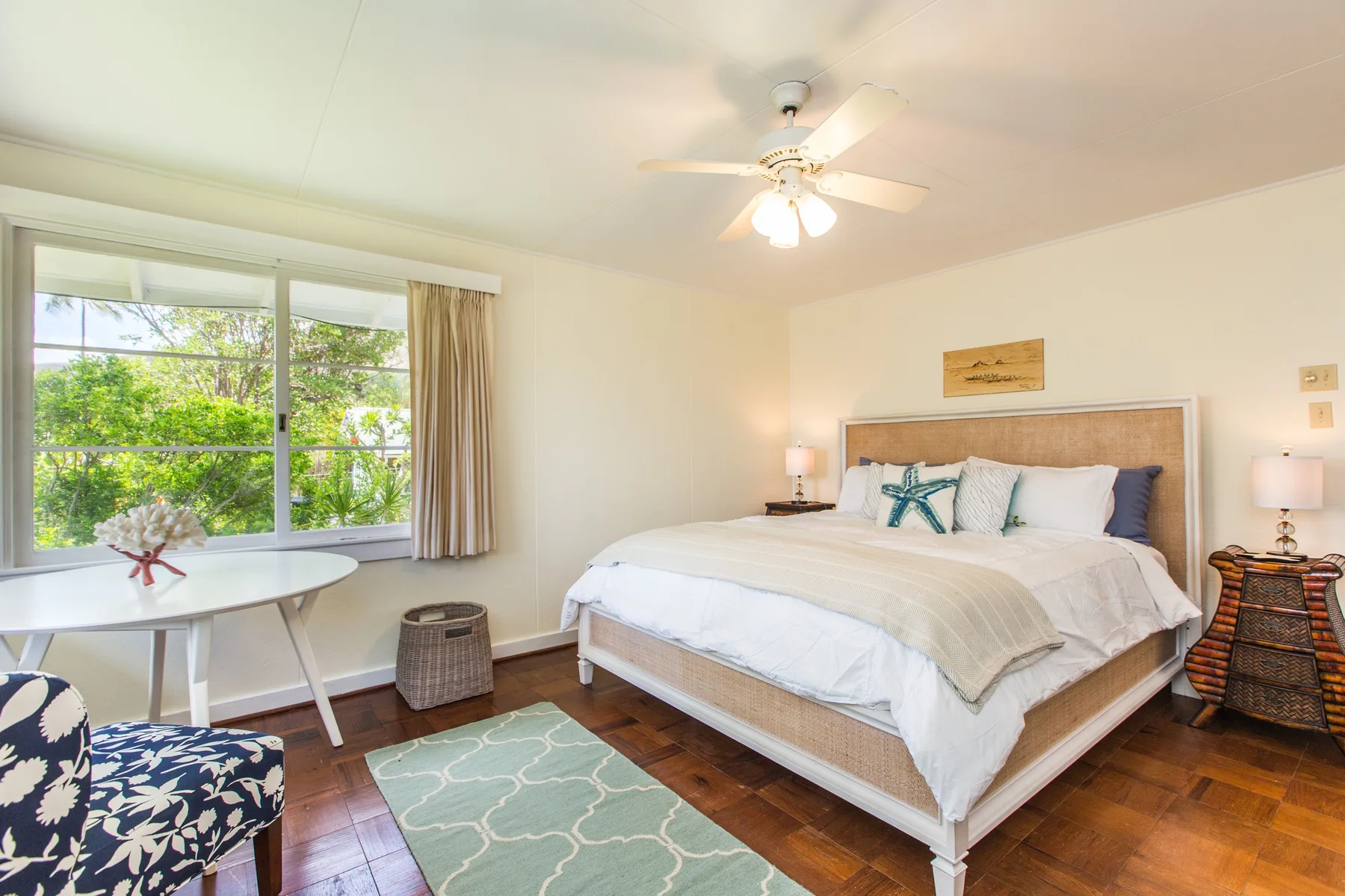 A bright bedroom with a bed, a large window, and a small table.
