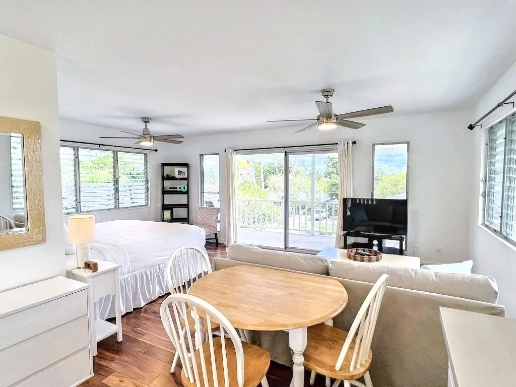 A bright living and dining area with a round wooden table beside a seating area.