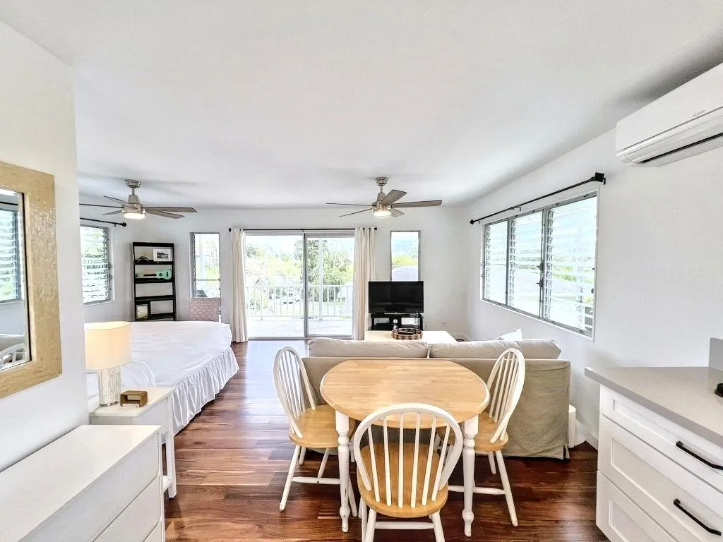 A bright living and dining area with a table, seating, and sliding glass doors.