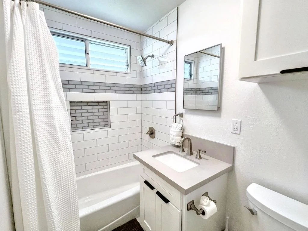A tiled bathroom with a bathtub, vanity sink, and toilet.