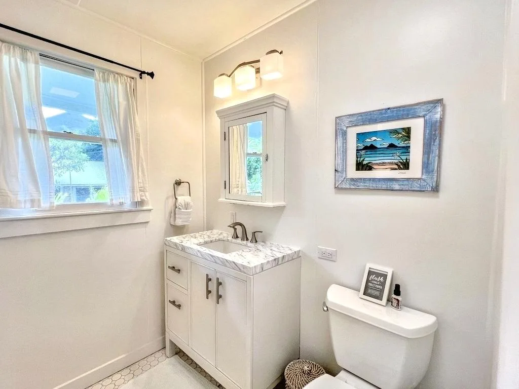 A bright bathroom with a white vanity, mirror, and toilet.