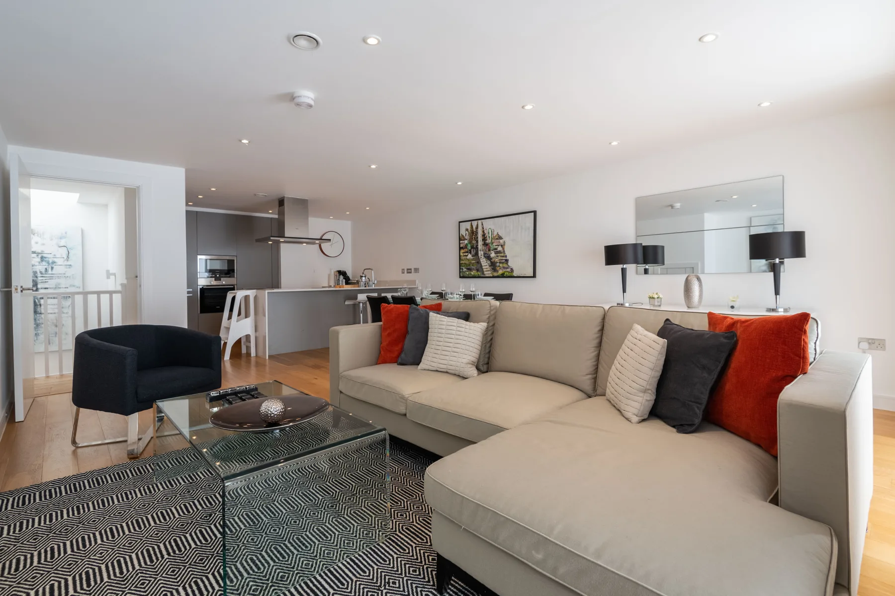 Living room with a sectional sofa, patterned rug, and open kitchen.