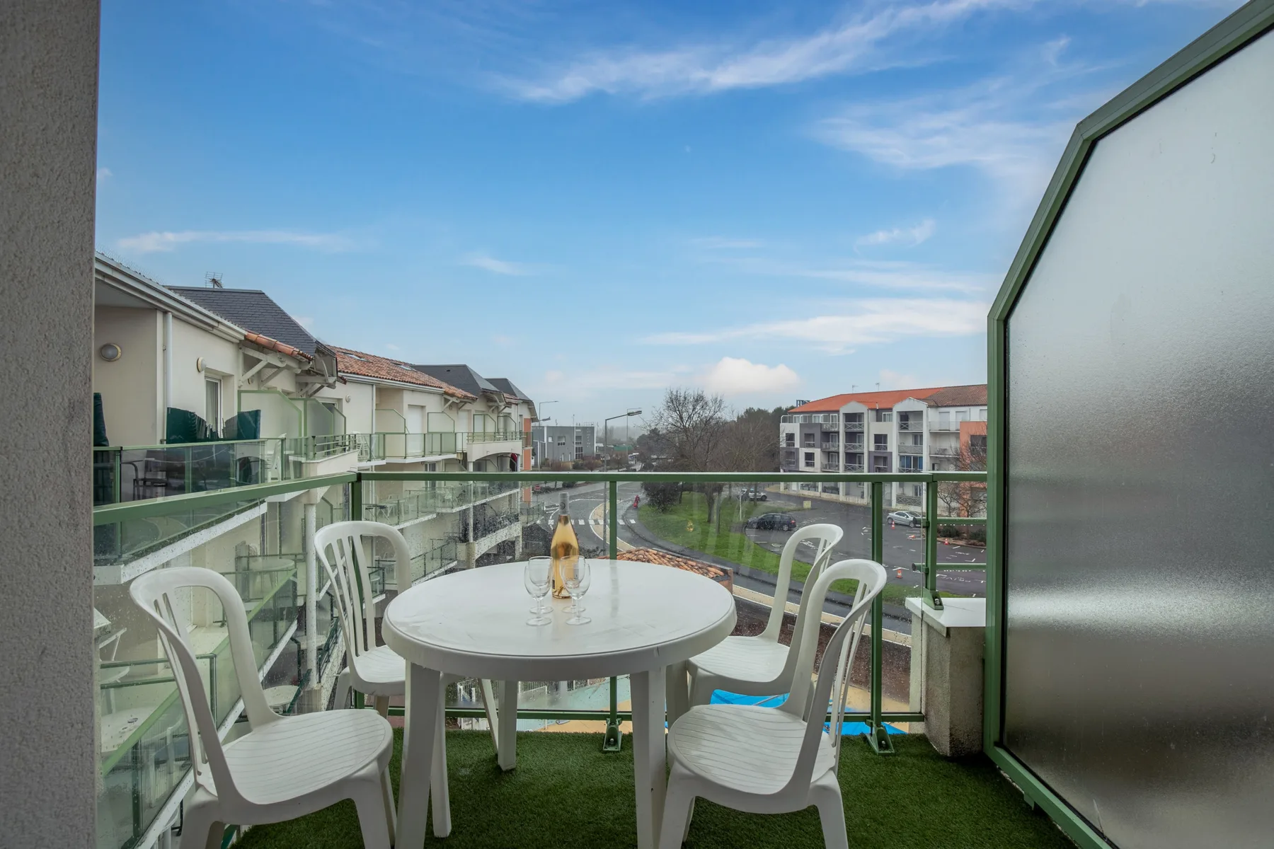 A balcony seating area with a round table overlooks nearby apartment buildings.