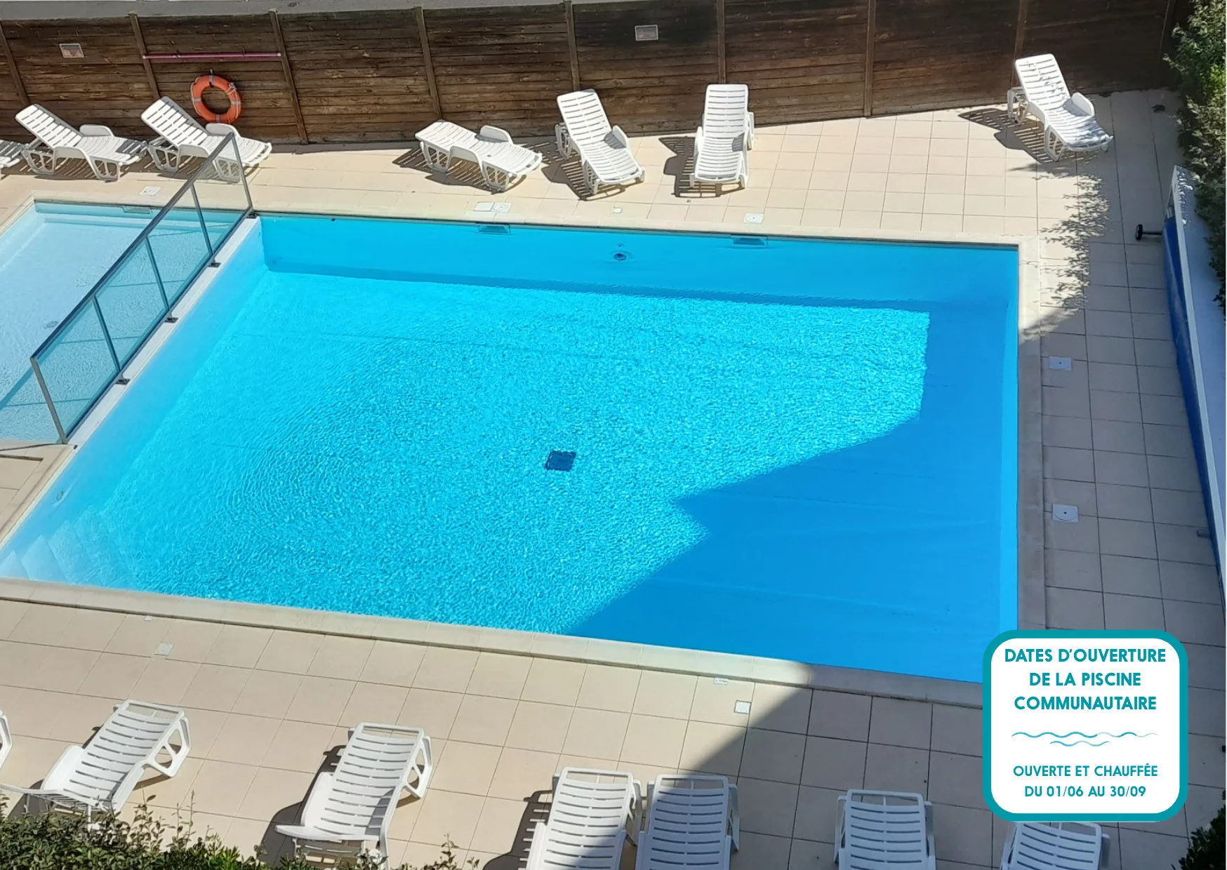 Outdoor swimming pool surrounded by lounge seating and a tiled deck.