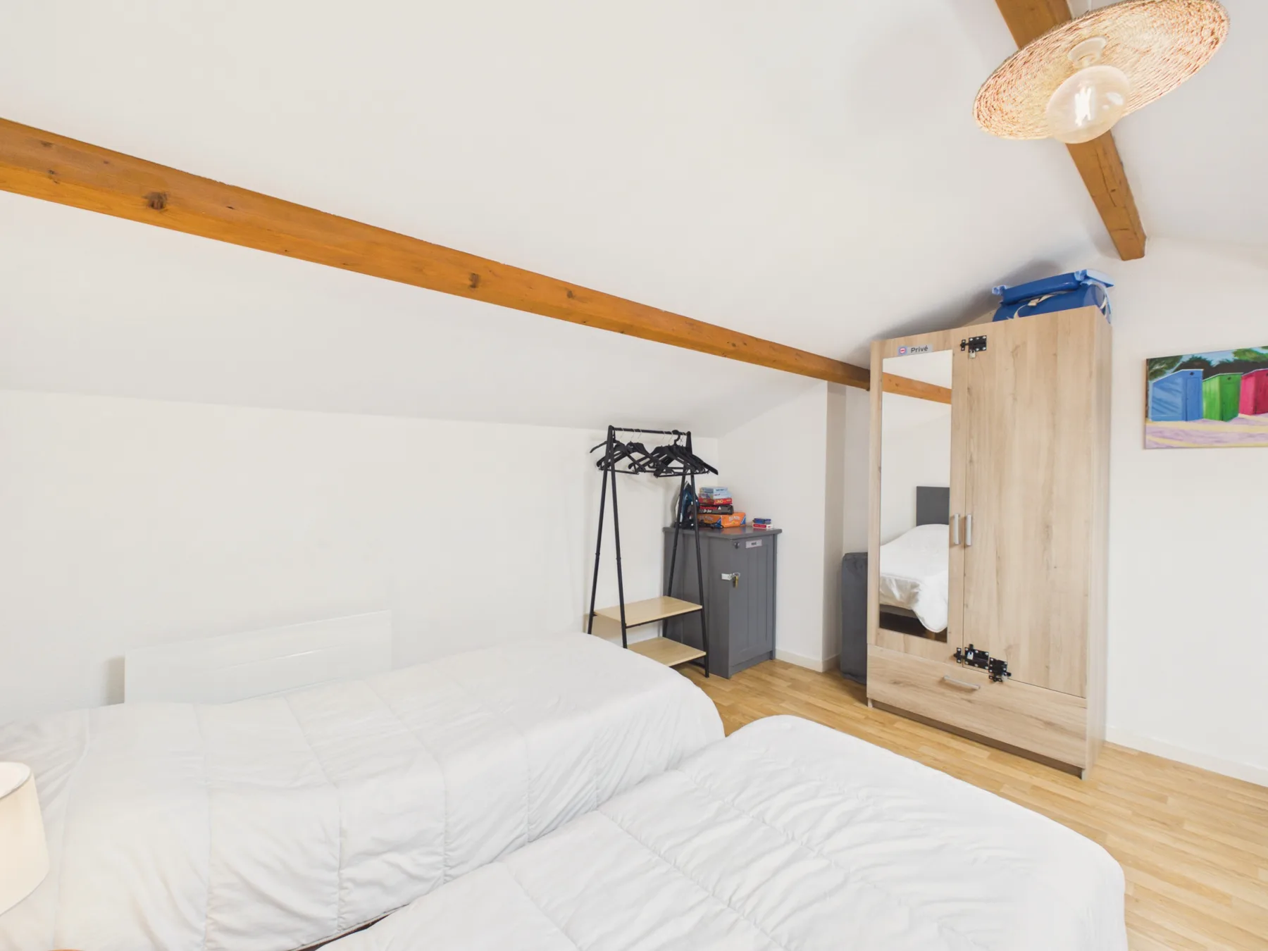 A bedroom with white bedding and a wooden wardrobe.