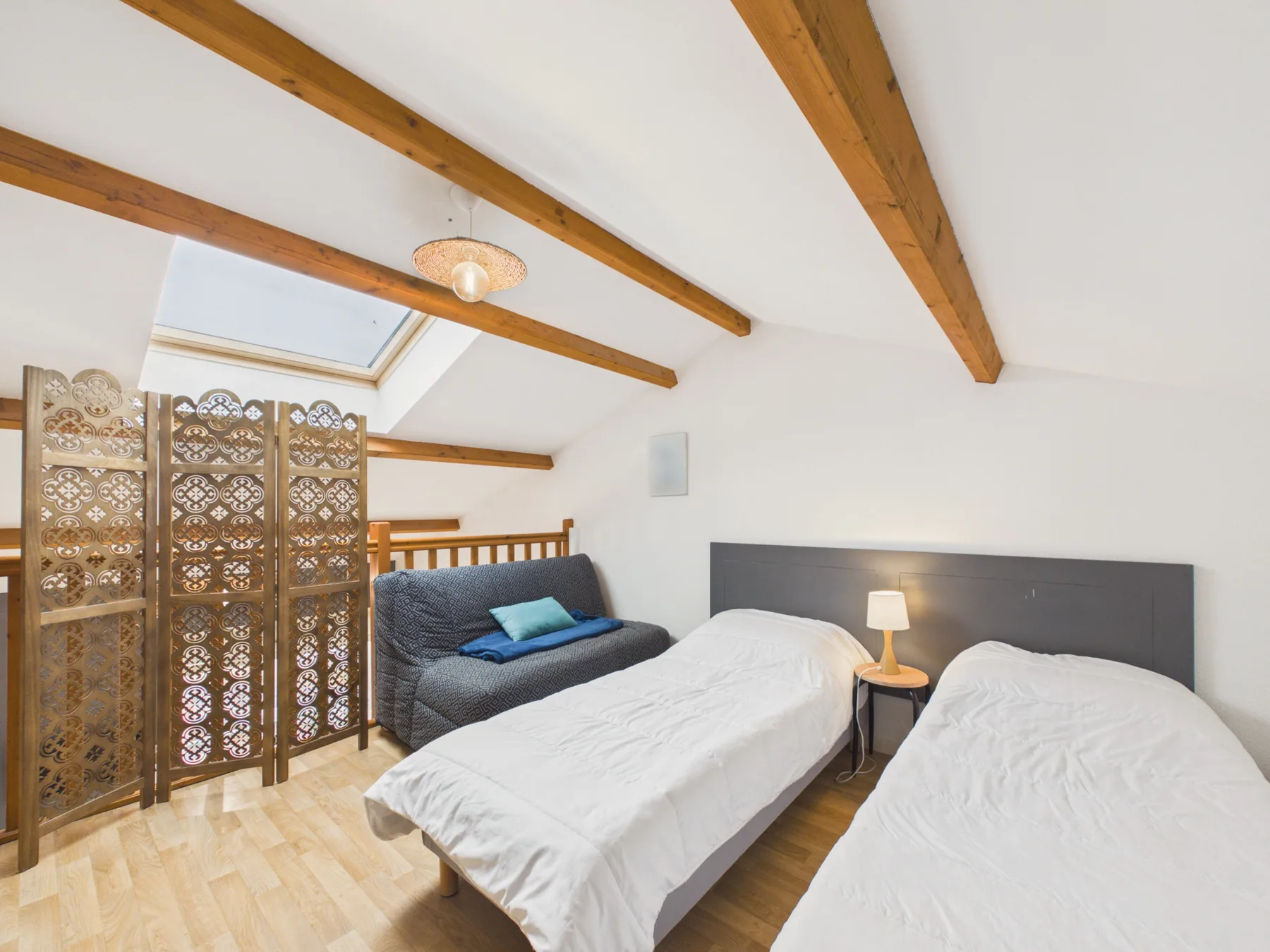 A bright bedroom with two beds and decorative wooden screens.