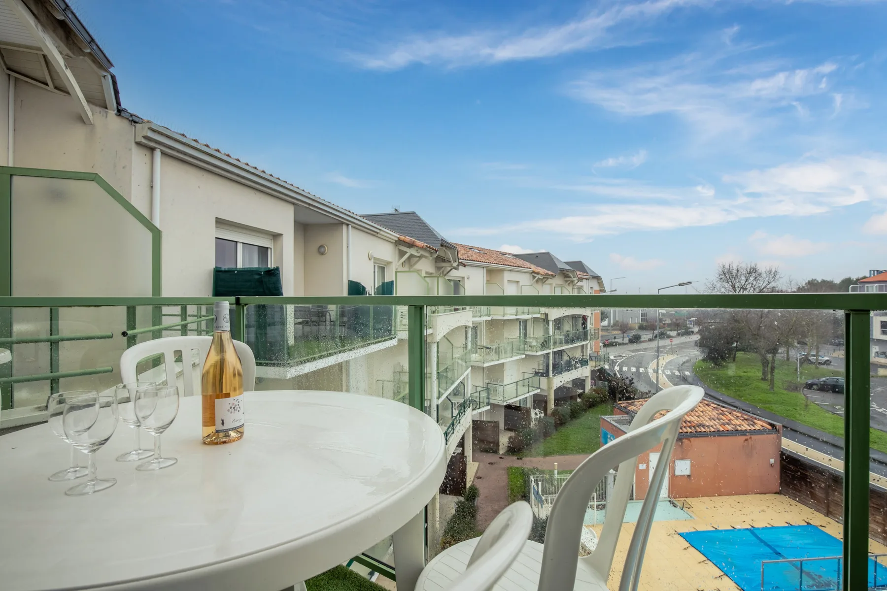 A balcony dining area overlooks neighboring buildings and a small outdoor pool.