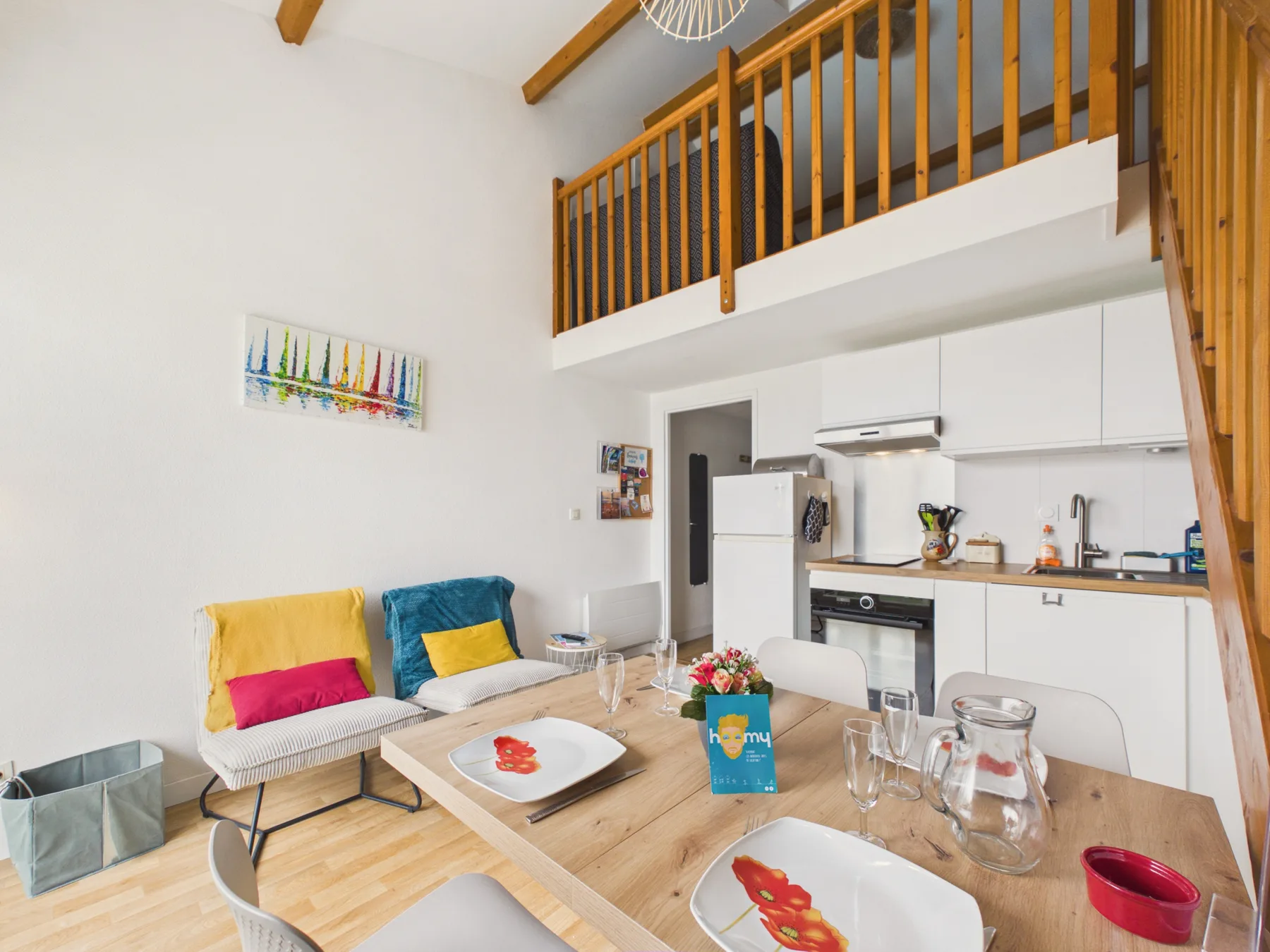 A bright open-plan kitchen and dining area sits beneath a wooden-railed mezzanine.