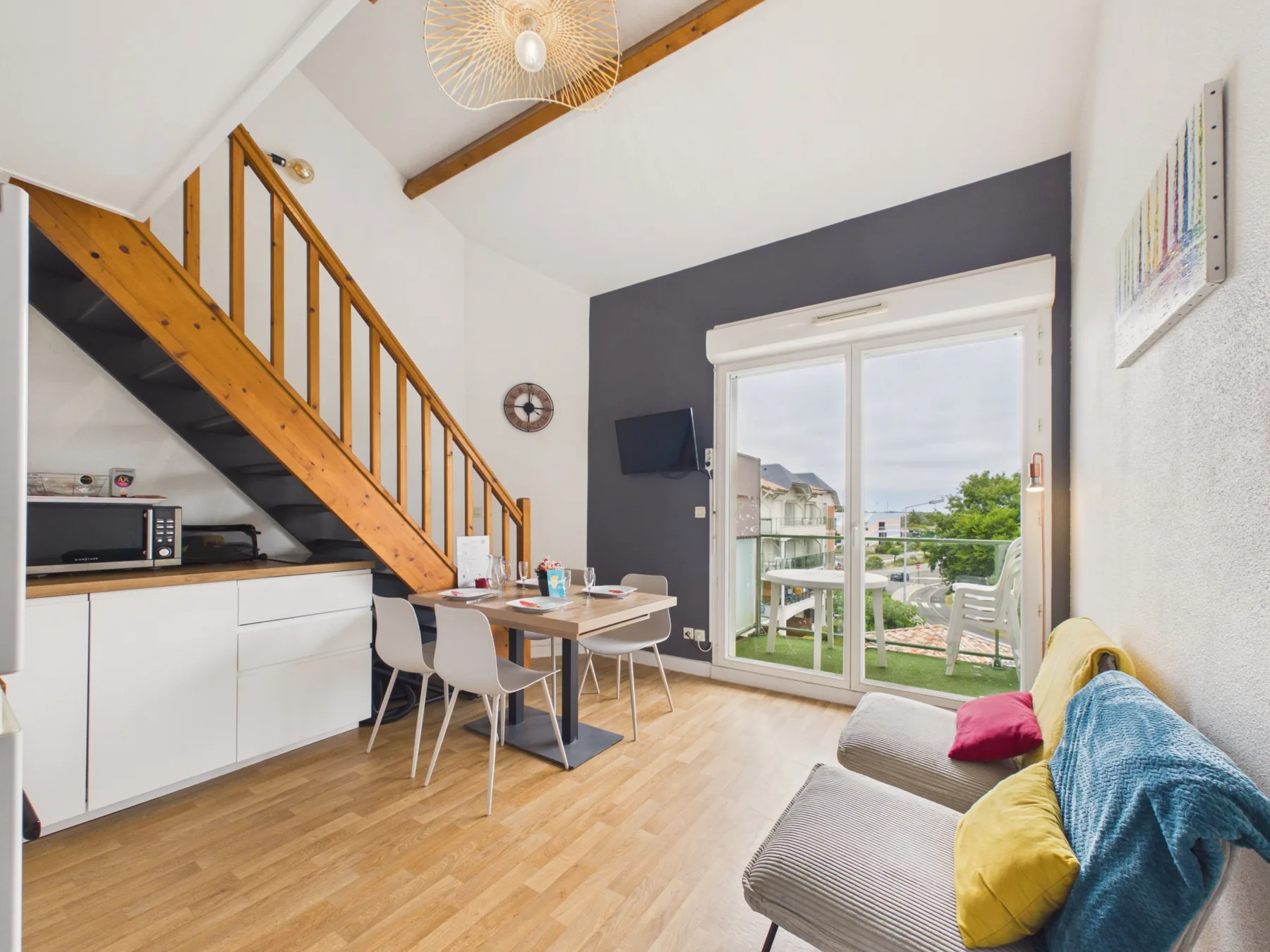 A bright living and dining area with a staircase and sliding glass doors.