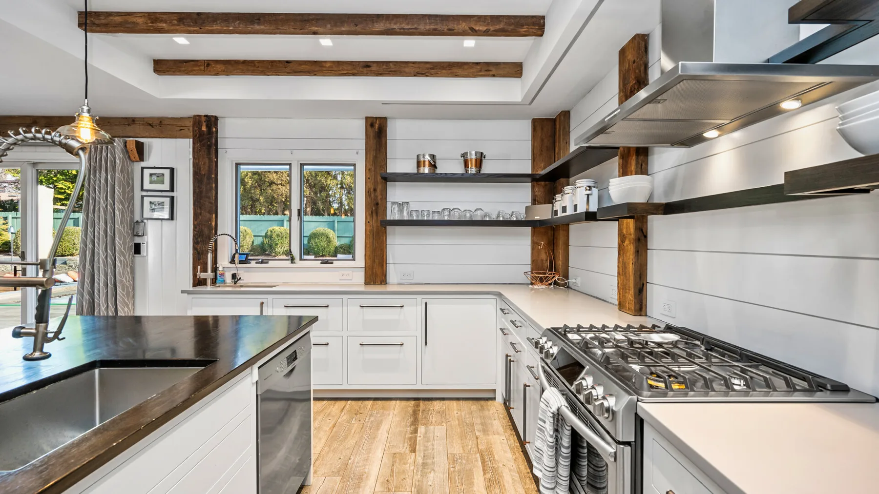 Una cocina luminosa con gabinetes blancos, una isla central y una estufa de acero inoxidable.