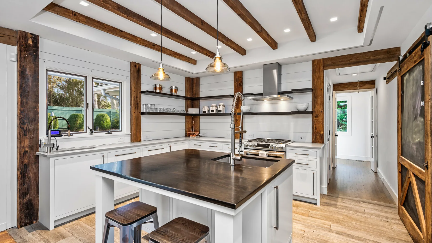Una cocina luminosa con una gran isla central y vigas expuestas en el techo.