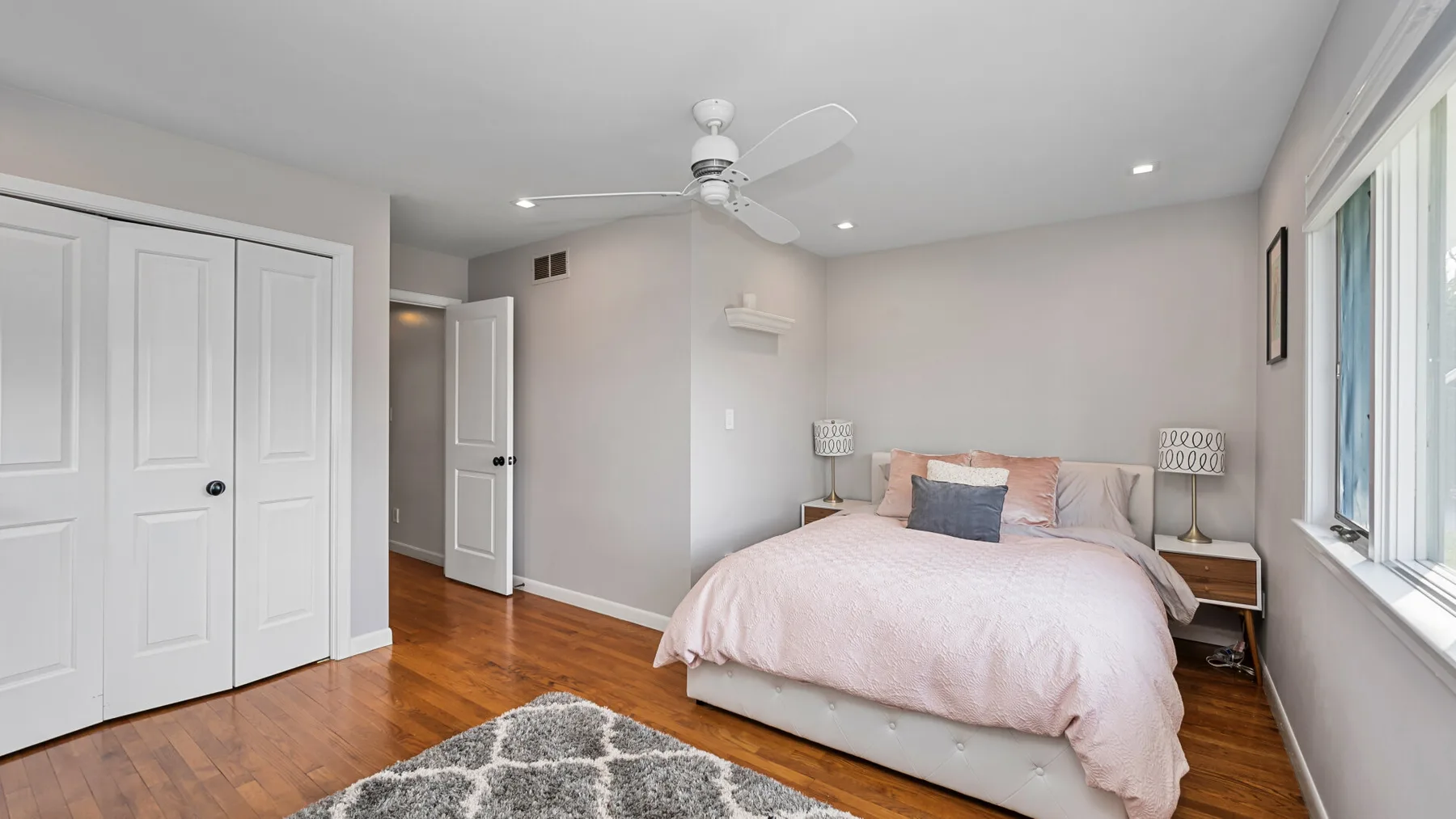 Un dormitorio con una cama, mesas de noche y un ventilador de techo.