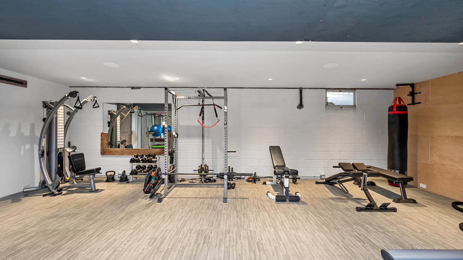 Una sala de ejercicio con máquinas, pesas y bancos de entrenamiento.