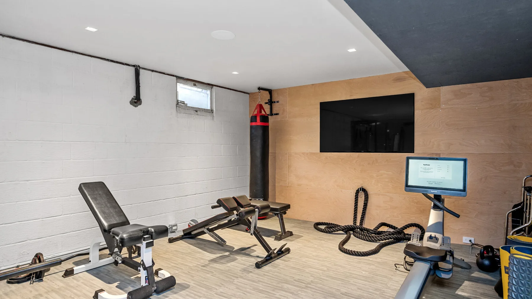 Un gimnasio en casa con bancos de ejercicio, pesas y cuerdas de entrenamiento.