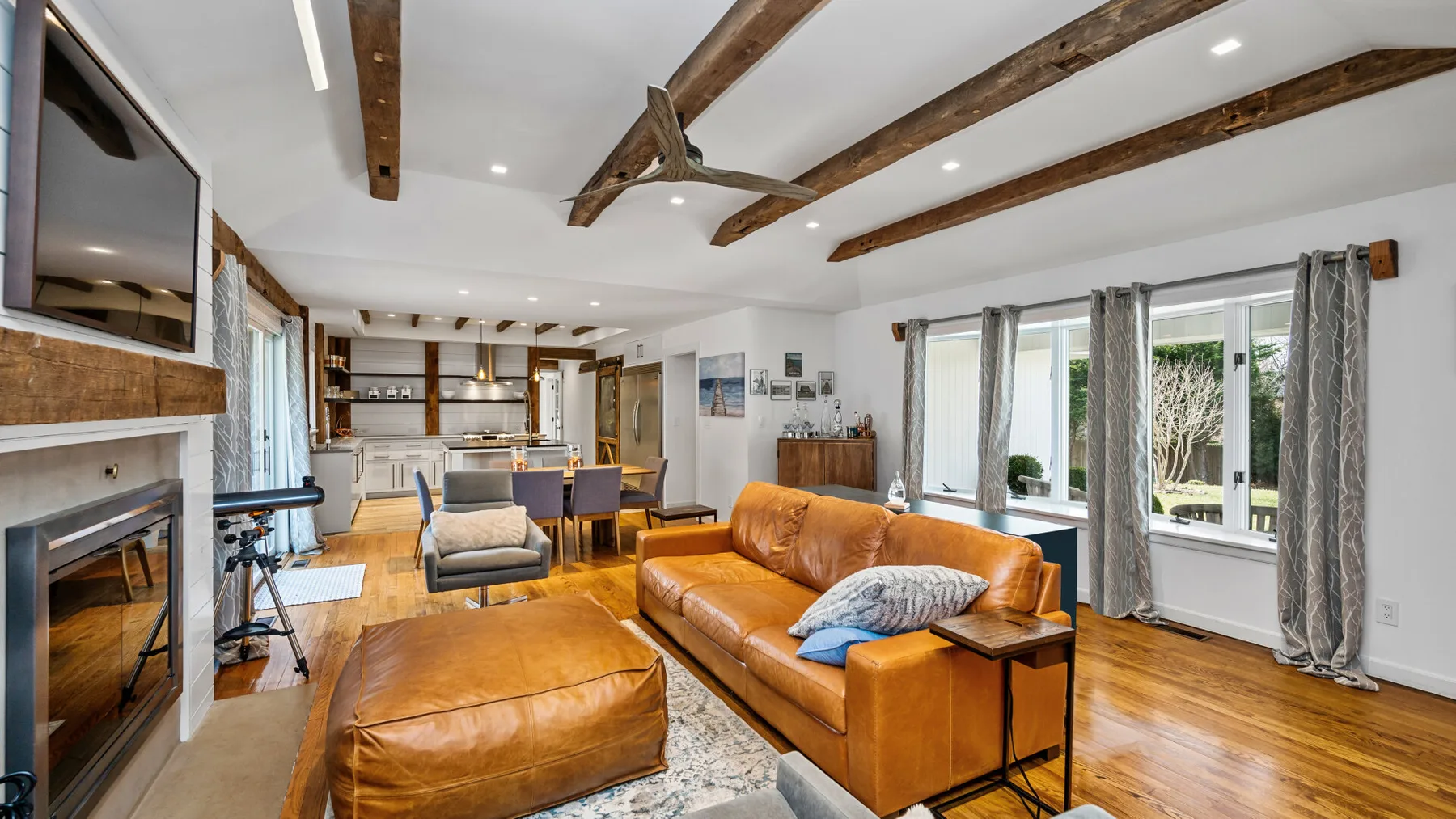 Una sala luminosa con asientos de cuero, vigas expuestas y ventanas grandes.