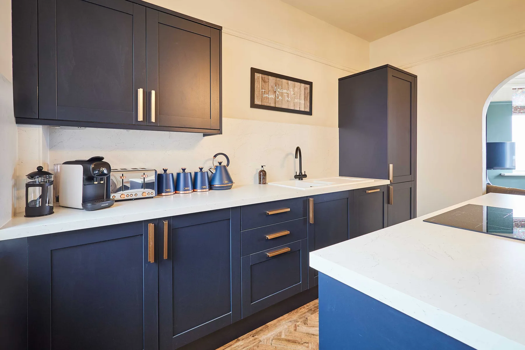 Una cocina moderna con gabinetes oscuros, una encimera blanca y una isla central.