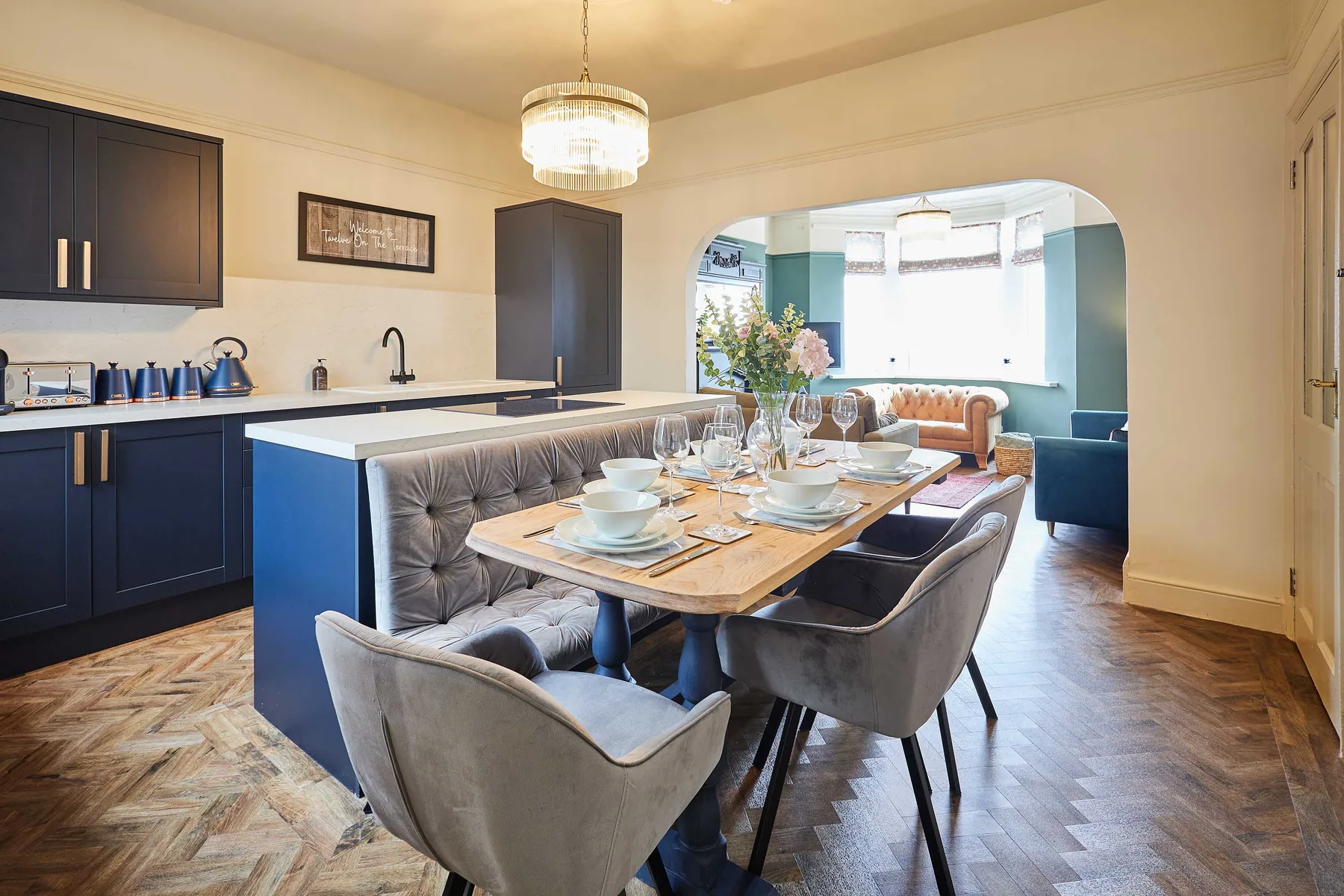 Una cocina y comedor de espacio abierto, con la mesa puesta y una sala contigua.