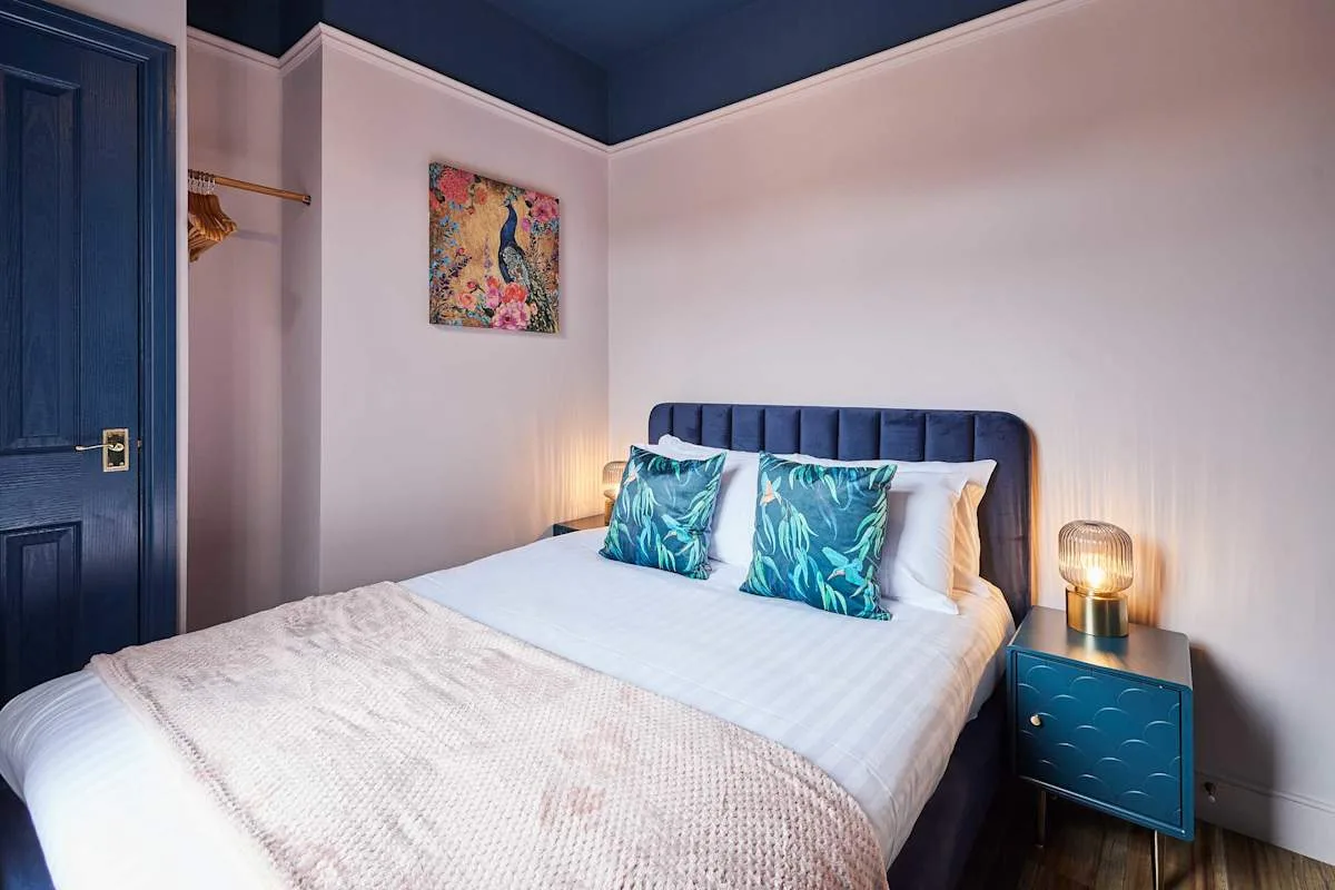 Un dormitorio con una cama, cojines coloridos y una mesita de noche.