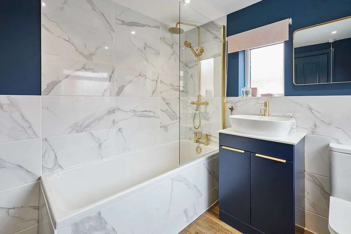 Un baño con bañera, mampara de ducha de vidrio y mueble azul marino.